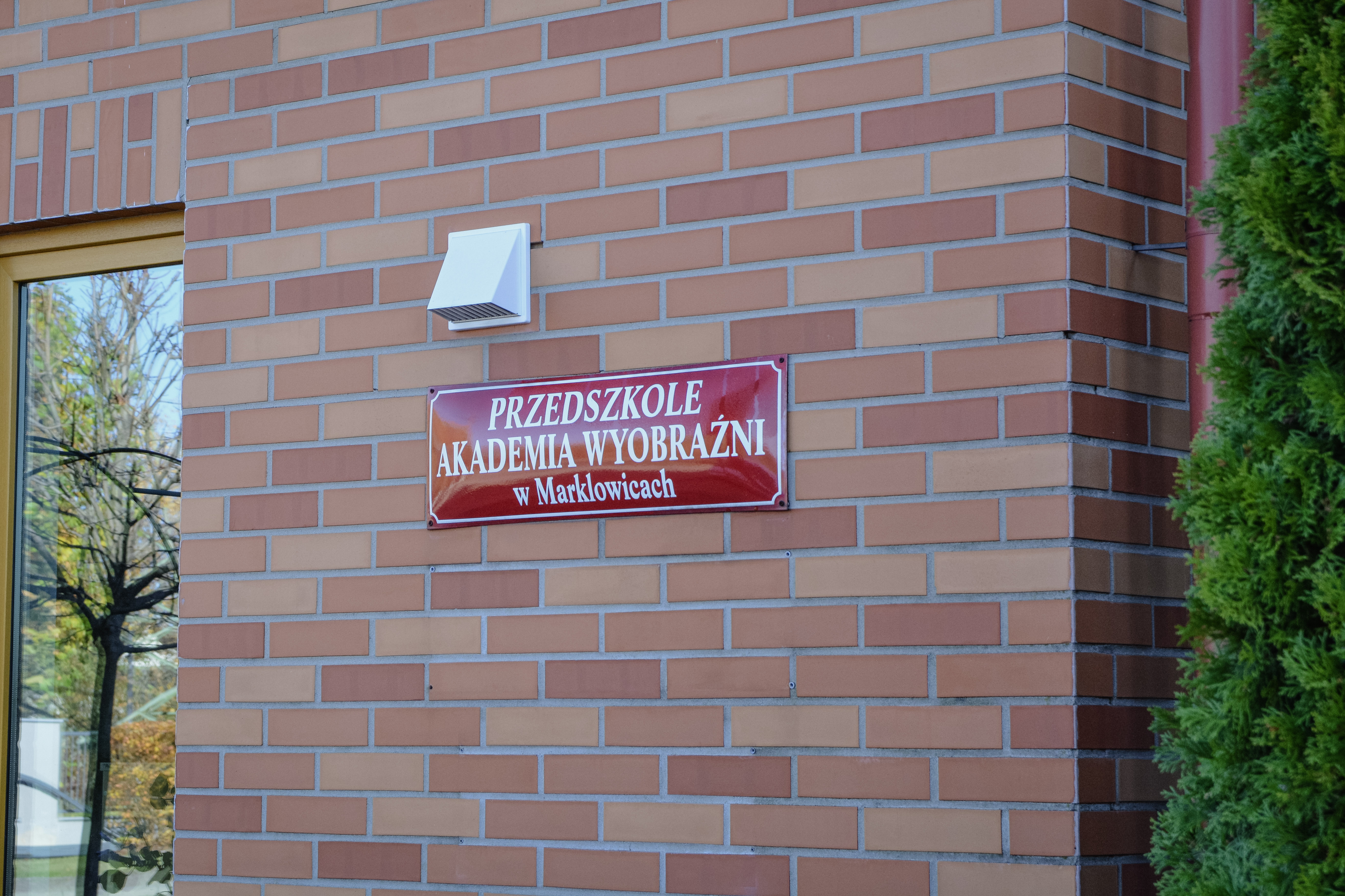 Fasada budynku z&nbsp;cegły z&nbsp;tabliczką z&nbsp;napisem "Przedszkole Akademia Wyobraźni w&nbsp;Marklowicach"