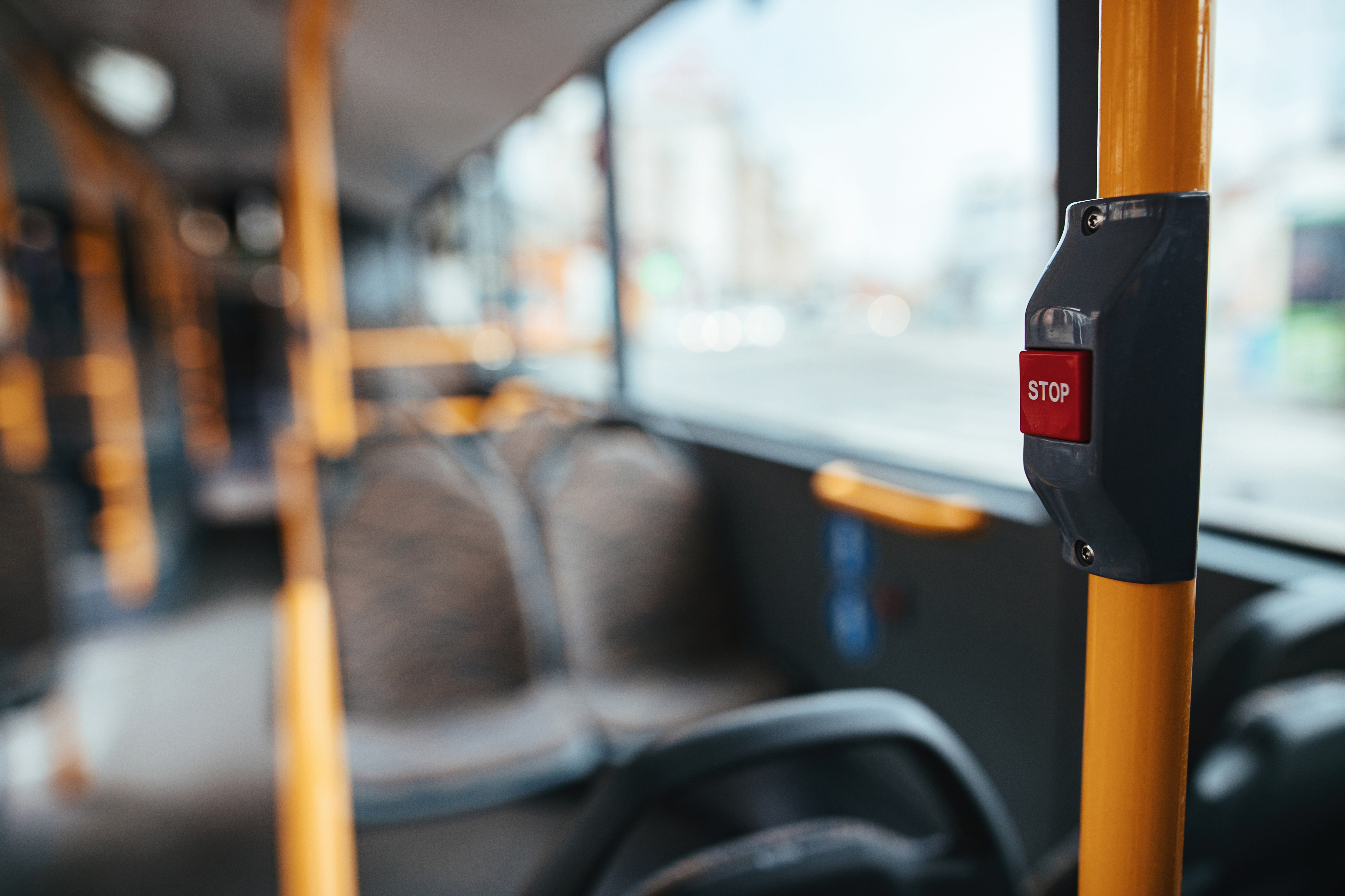 Puste wnętrze autobusu z&nbsp;widocznymi siedziskami oraz&nbsp;przyciskiem STOP na&nbsp;ż&oacute;łtym słupku
