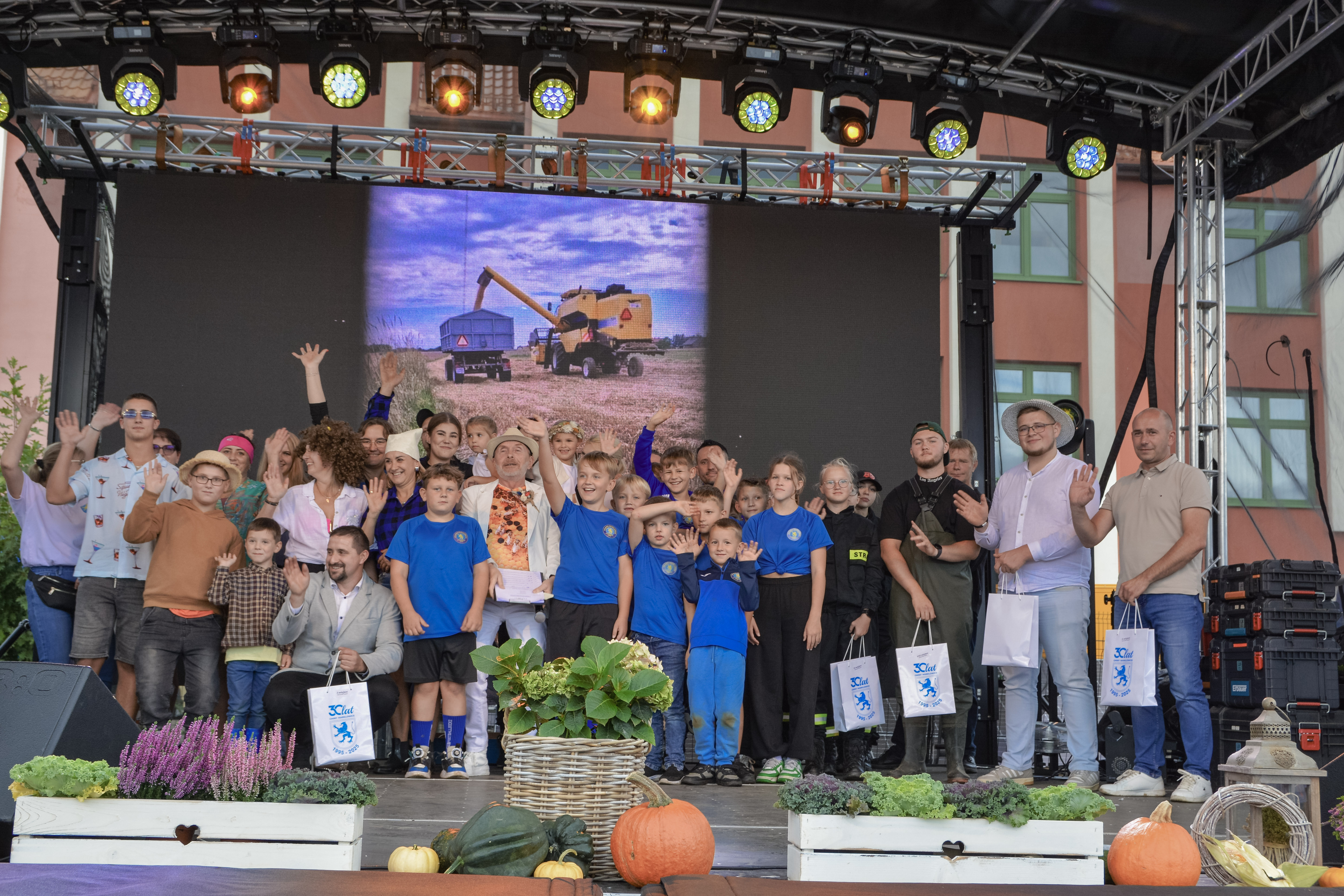 Na scenie grupa os&oacute;b nagrodzonych w&nbsp;konkursie na&nbsp;najlepszy pojazd w&nbsp;korowodzie dożynkowym