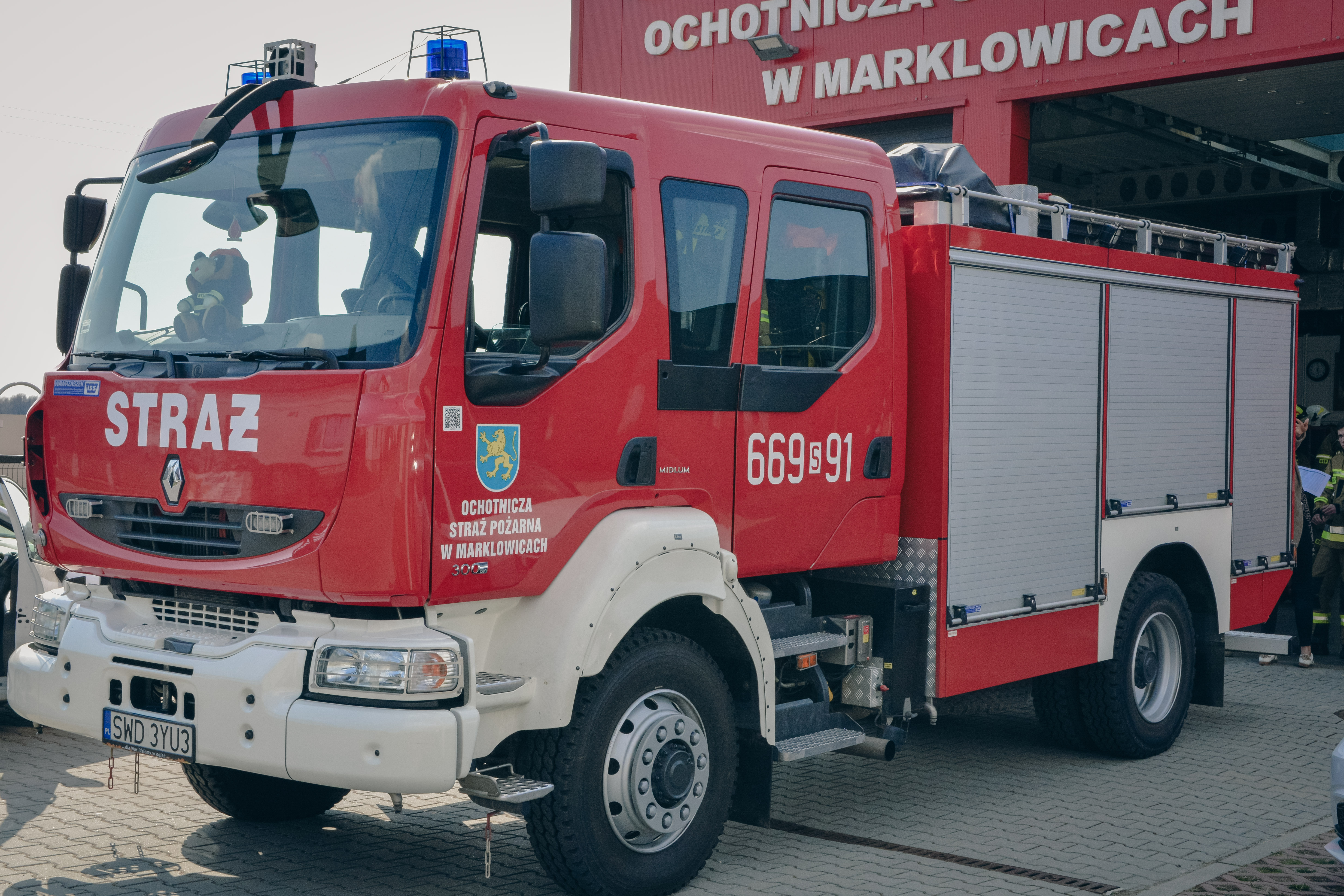 Czerwony w&oacute;z strażacki stoi przed remizą z&nbsp;napisem Ochotnicza Straż Pożarna w&nbsp;Marklowicach