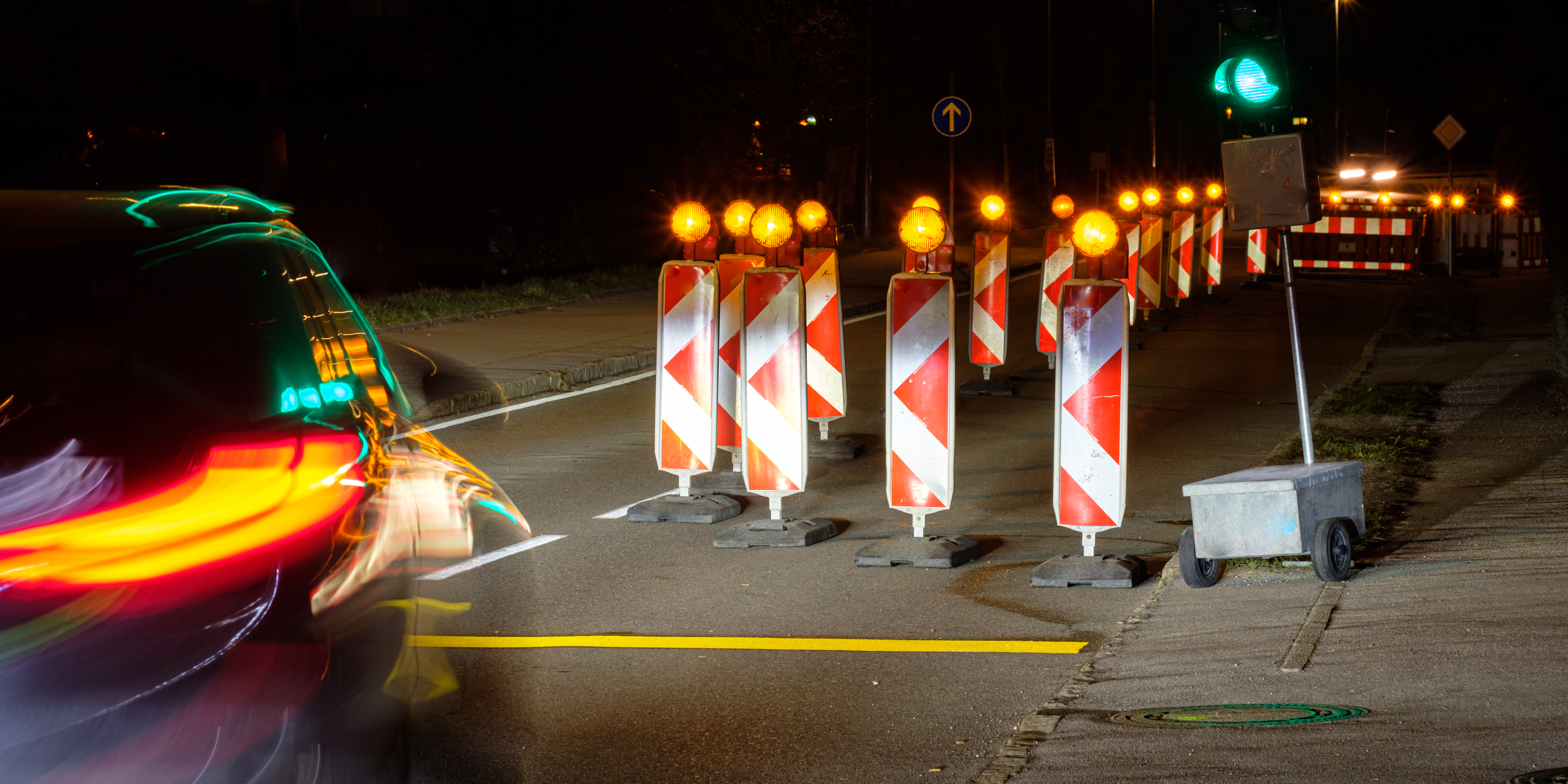 Tymczasowa sygnalizacja świetlna, aktywne zielone światło, noc, słupki ostrzegawcze z&nbsp;migającym pomarańczowym światłem