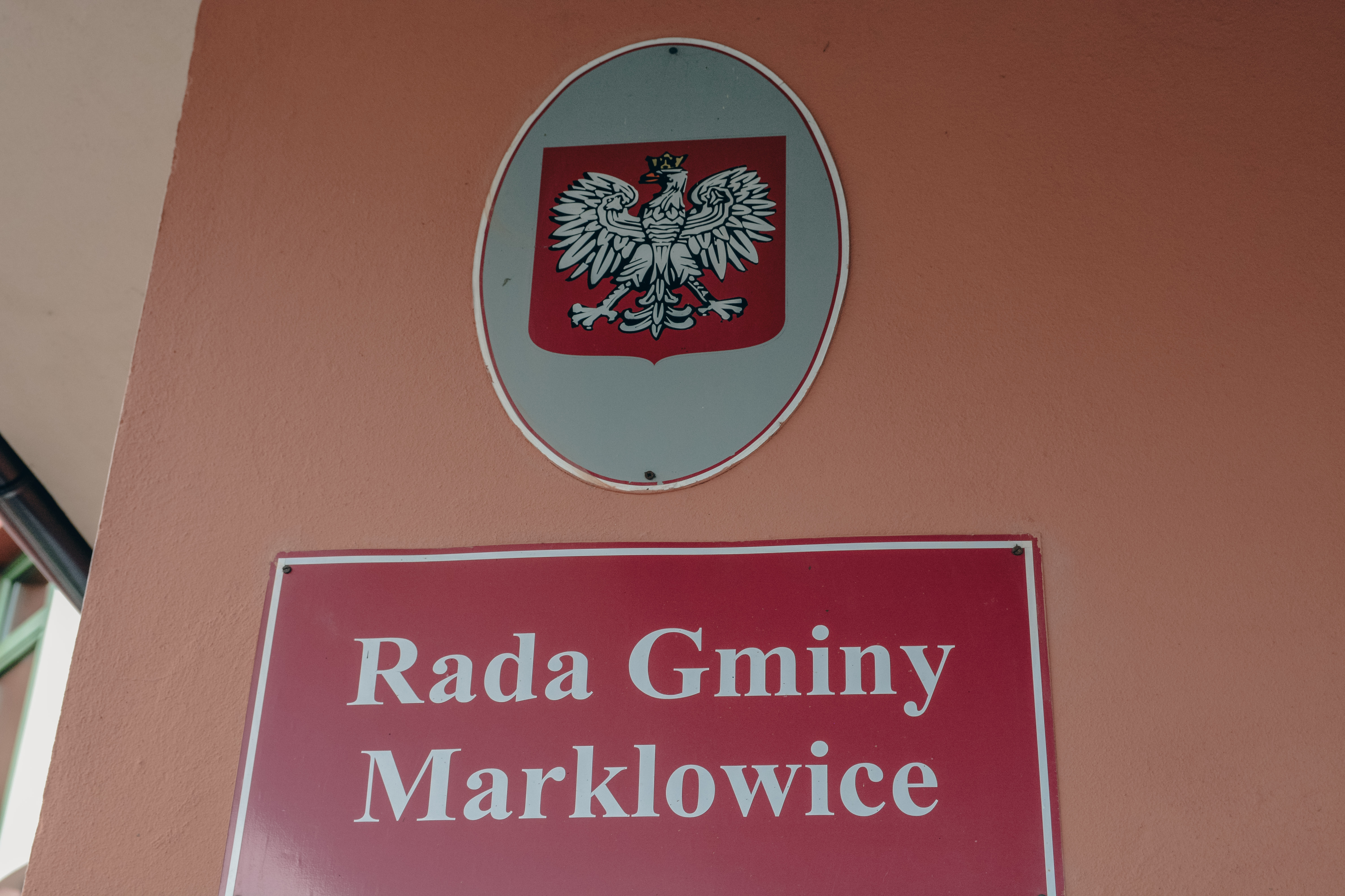 Na elewacji budynku widoczny emblemat z&nbsp;godłem Polski, poniżej czerwona tabliczka z&nbsp;napisem "Rada Gminy Marklowice"