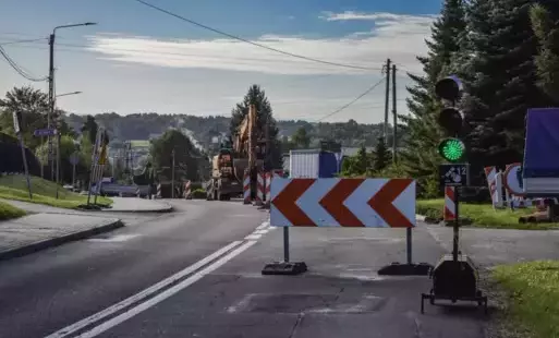 Droga z zamkniętym jednym pasem ruchu, z tymczasową sygnalizacją świetlną oraz pracującą koparką w tle