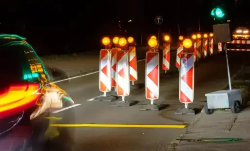 Tymczasowa sygnalizacja świetlna, aktywne zielone światło, noc, słupki ostrzegawcze z migającym pomarańczowym światłem
