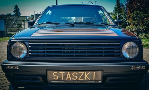 Zdjęcie karoserii samochodu od frontu z bliska, tablica rejestracyjna z napisem "STASZKI"