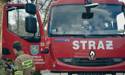 Wóz bojowy straży bożarnej OSP Marklowice z przodu, na otwartych drzwiach samochodu herb Gminy Marklowice, strażak OSP przechodzi obok samochodu